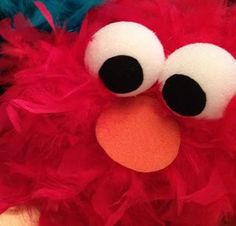 a close up of a red stuffed animal with big eyes and a nose that looks like an angry bird