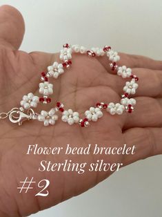 a hand holding a beaded bracelet with red and white beads