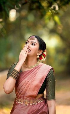 a woman in a sari is holding her hand to her face and looking up