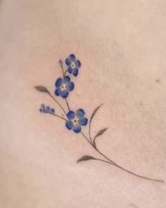 a small blue flower tattoo on the back of a woman's shoulder and chest