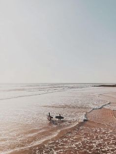 two surfers walking into the ocean with their surfboards