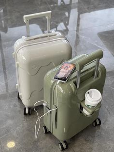 two pieces of luggage sitting next to each other on top of a tile floor with a cell phone hooked up to it