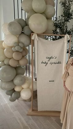 a baby is standing next to a bunch of balloons