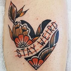 a tattoo with the words stay weird written on it's side and flowers in the shape of a heart