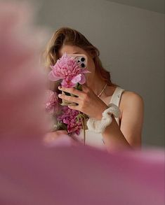 a woman taking a selfie with her cell phone and flowers in front of her