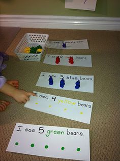 a child is sitting on the floor and playing with cut out paper animals that read i see 5 green bears