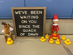 two elf dolls are next to a sign that says we've been waiting on you since the quack of dawn