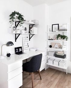 a white desk topped with a computer monitor next to a book shelf filled with books