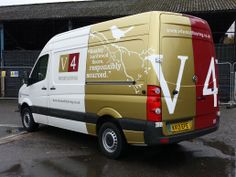 a van parked in front of a building on a wet parking lot next to a fence