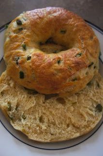 two bagels sitting on top of each other on a white plate with black trim