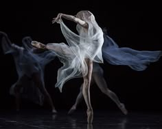 three ballet dancers in motion on a stage