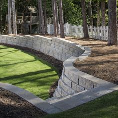 a brick retaining wall with grass and trees in the background