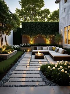 an outdoor living area with couches, fire pit and landscaping lighting in the evening