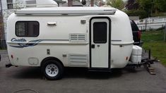 an old camper trailer parked in a parking lot with the door open and windows closed