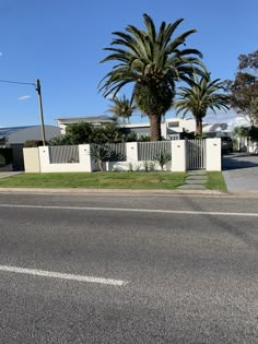 an empty street with palm trees and houses in the backgrouds, on a sunny day