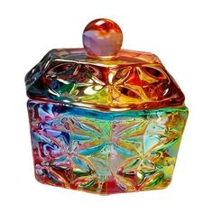 a multicolored glass box with an apple sitting on it's top and lid