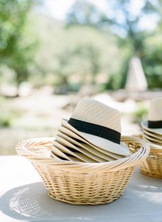 two hats sitting in a basket on top of a table