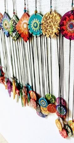 a bunch of colorful buttons hanging on the side of a wall with long black cords