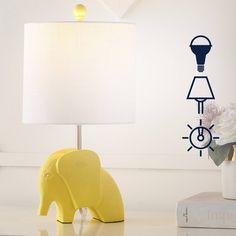 an elephant lamp sitting on top of a table next to a white vase with flowers