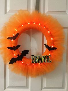 an orange tulle wreath with bats and beware written on it, hanging from the front door