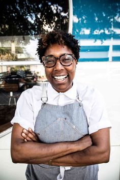 a woman with glasses and an apron is smiling