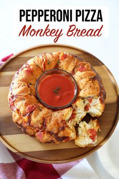 pepperoni pizza monkey bread on a wooden plate with a dipping sauce in the middle