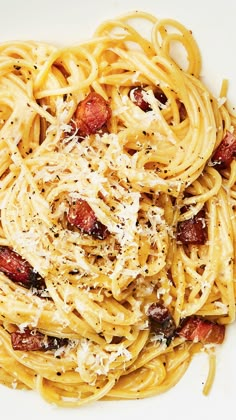 pasta with bacon and parmesan cheese on a white plate, ready to be eaten