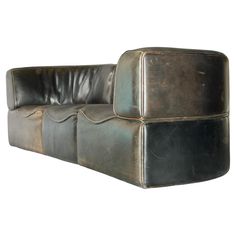 a black leather couch sitting on top of a white wall