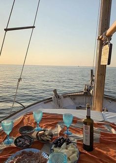 the table is set with wine, cheese and crackers on an ocean sailboat