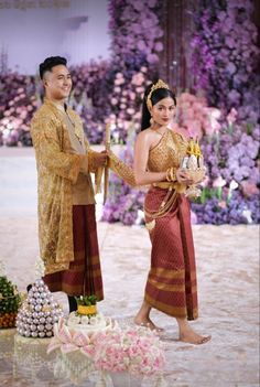 a man and woman standing next to each other in front of a flower arrangement on the ground