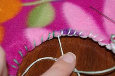 someone is stitching something on a piece of fabric with needle and thread in front of them