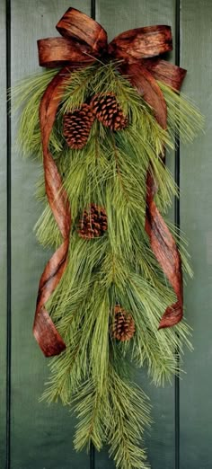 a pine cone and ribbon hanging on a door