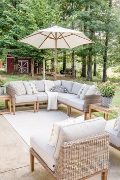 an outdoor living area with wicker furniture and large umbrella over the couches in front of it