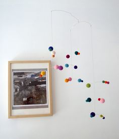 a framed photo hanging on the wall next to a string of pom - poms