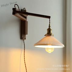 a light that is hanging from a wall next to a white wall with writing on it