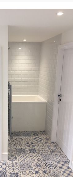 a bathroom with blue and white tiles on the floor, walls and bathtub in the corner