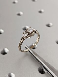 a diamond ring sitting on top of a piece of metal next to a pair of scissors