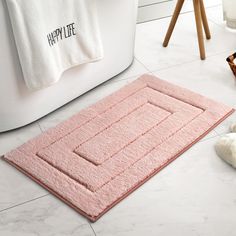 a bath mat on the floor next to a pair of slippers and a teddy bear