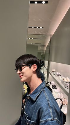 a man with glasses standing in front of a display case filled with pairs of shoes