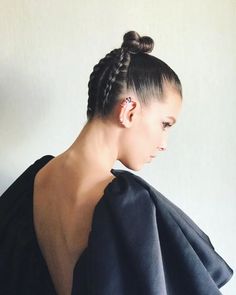 a woman with her back turned to the side, wearing a black dress and braided hair