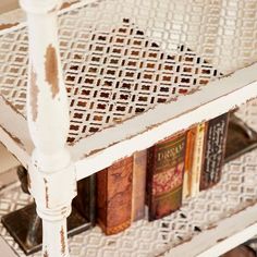 a white shelf with books on top of it and an iron grate in the bottom