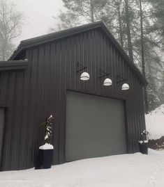 two garages in the snow with lights above them and trees behind them on a foggy day