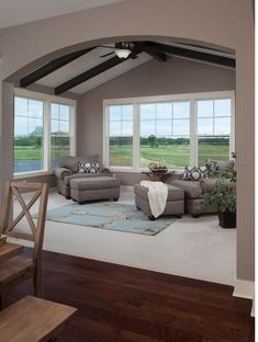 a living room filled with furniture and windows overlooking a large open field in the distance