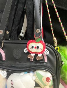 a handbag with an apple on it and other stuffed animals in the back pocket