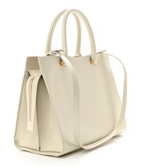 This is an authentic SAINT LAURENT Shiny Calfskin Medium Uptown Tote in Crema Soft. This tote is crafted of smooth calfskin leather in off white. The bag features rolled leather top handles, optional shoulder strap with polished gold-tone hardware and a front pocket. The top zipper opens to a black partitioned fabric interior with a patch pocket. Leather Top, Front Pocket, Patch Pocket, Calf Skin, Saint Laurent, Shoulder Strap, Gold Tones, Handles, Off White