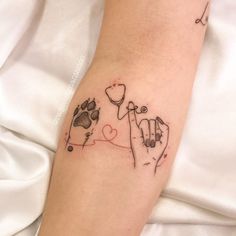 a person with a tattoo on their arm holding a dog's paw and heart