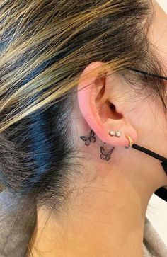 a woman with a small butterfly tattoo on her left side behind the ear is wearing a black ribbon