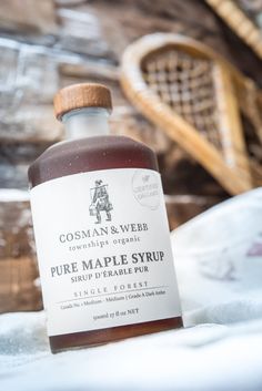 a bottle of pure maple syrup sitting on top of a tablecloth next to a basket