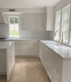 an empty kitchen with white cabinets and wood floors