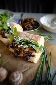 the sandwich is cut in half on the cutting board with mushrooms and other food items